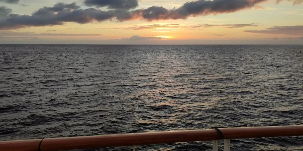 Sonnenuntergang über dem Meer, vorn die Reling einer Fähre