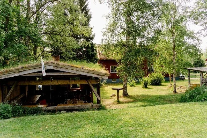 Grillhütte mit Grasdach neben einer Wiese
