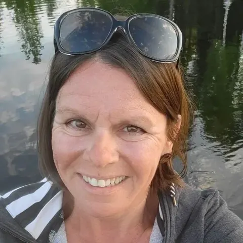 Eine Gästin lächelt am See in die Kamera