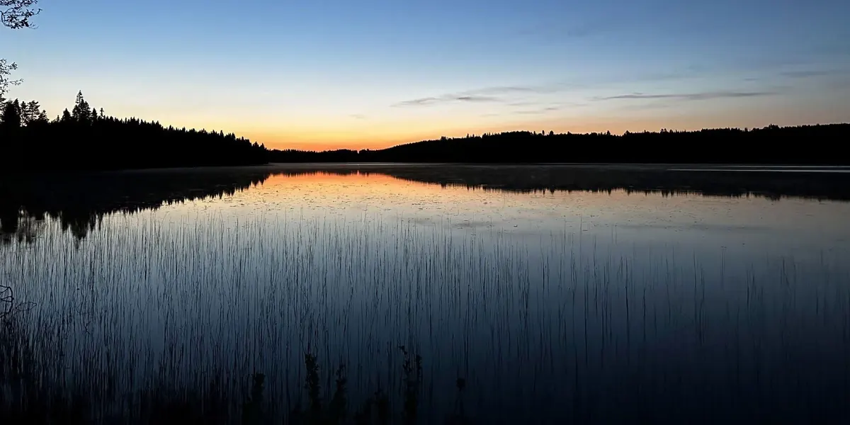 See in der Dämmerung mit Spiegelung der Wälder
