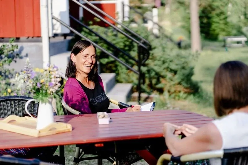 Zwei Frauen an einem roten Gartentisch auf der Terrasse