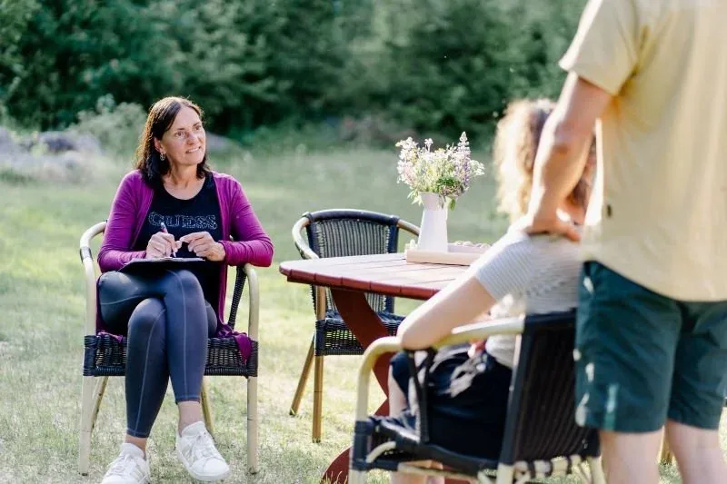 Zwei Frauen an einem Gartentisch, daneben ein Mann