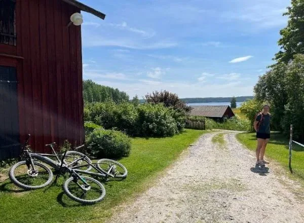 Fahrräder im Gras neben einem Kiesweg, im Hintergrund der See