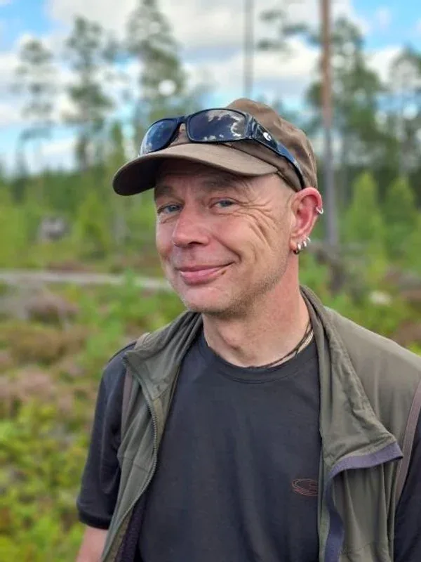 Gast mit Cap vor Kiefern, im Hintergrund Wald