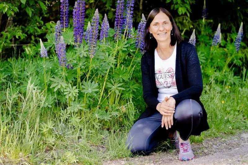 Nicole hockt im blühenden Lupinenfeld