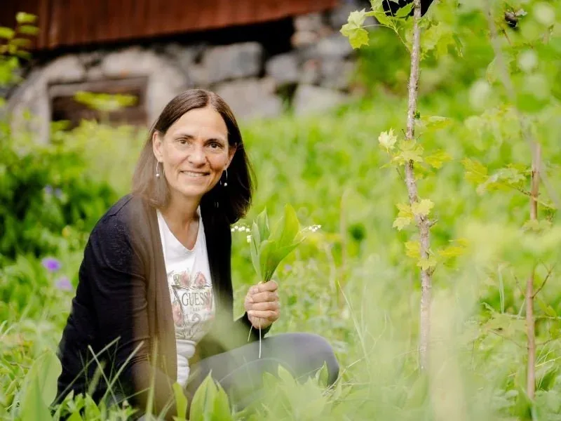 Nicole lehnt im grünen Gras an einer Holzwand