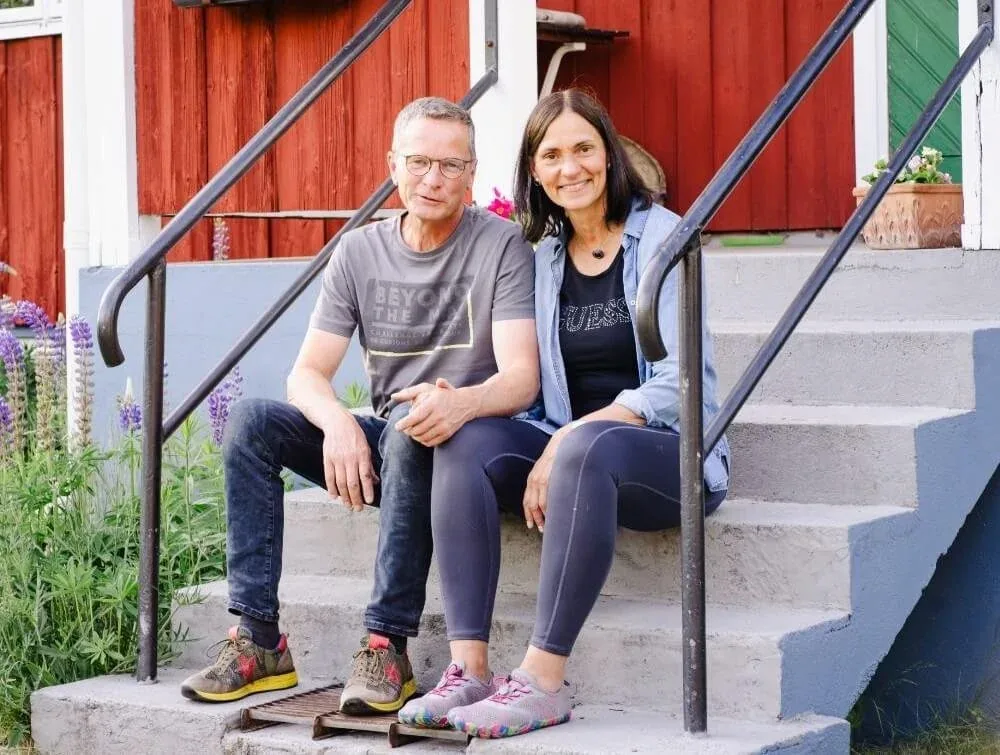 Nicole und Rainer sitzen auf der Treppe vor dem roten Haus
