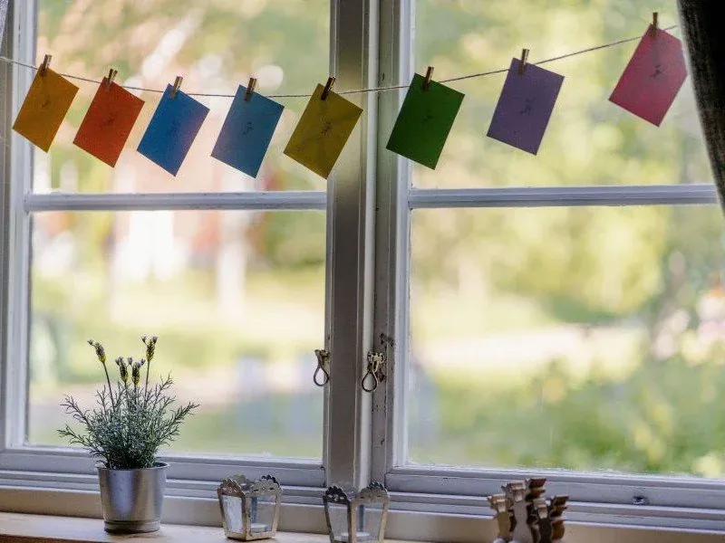 Bunte Wimpelkette vor einem Fenster am Wald