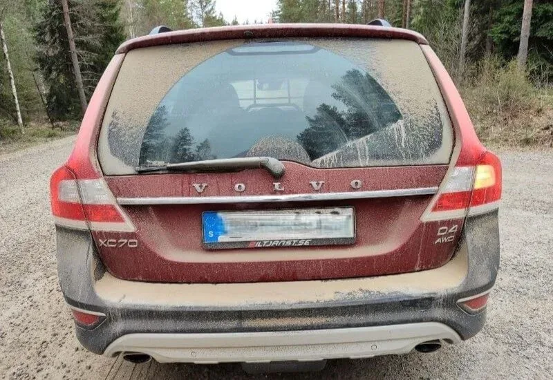 Rotes Auto mit Staub auf einer Schotterstraße