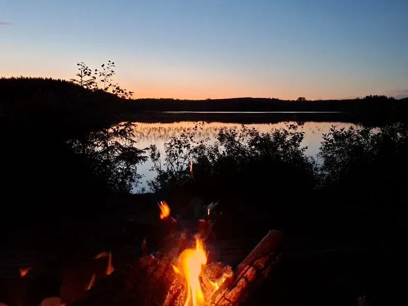 Lagerfeuer am See in der Dämmerung