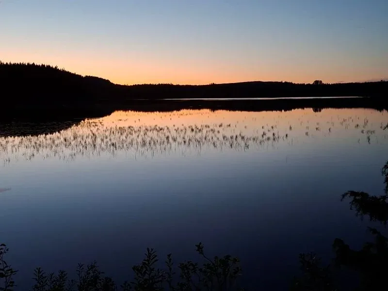 Dämmerung am See, ein Streifen Orange über dem stillen Wasser