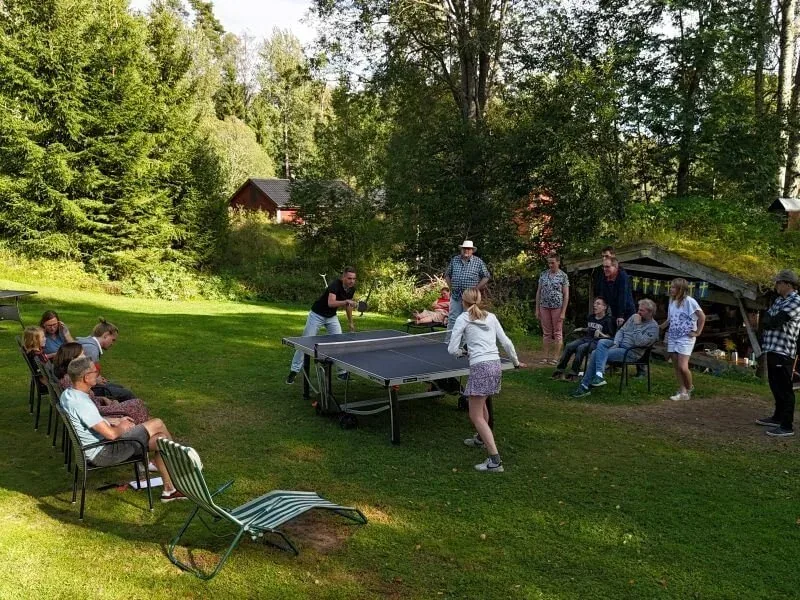 Gäste spielen Tischtennis im Garten, andere sitzen in Liegestühlen
