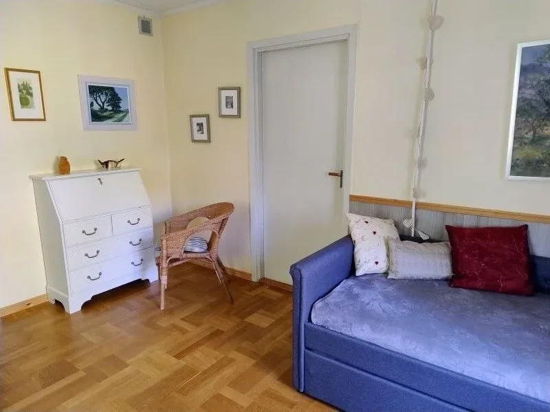 Kleines Zimmer mit Kommode und blauem Schlafsofa