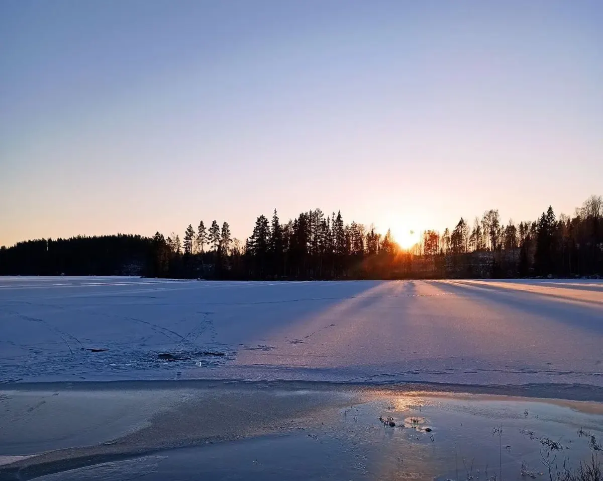 Sonnenuntergang über dem verschneiten, zugefrorenen See