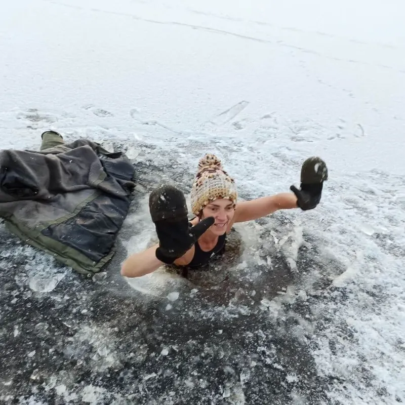 Person im Eisloch im verschneiten See