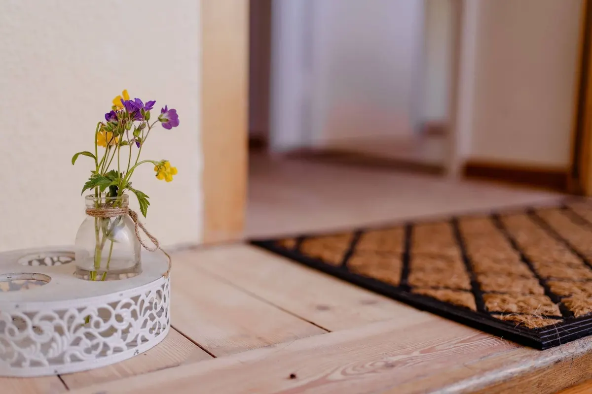 Blumen in einer Vase auf der Kommode neben der Fußmatte