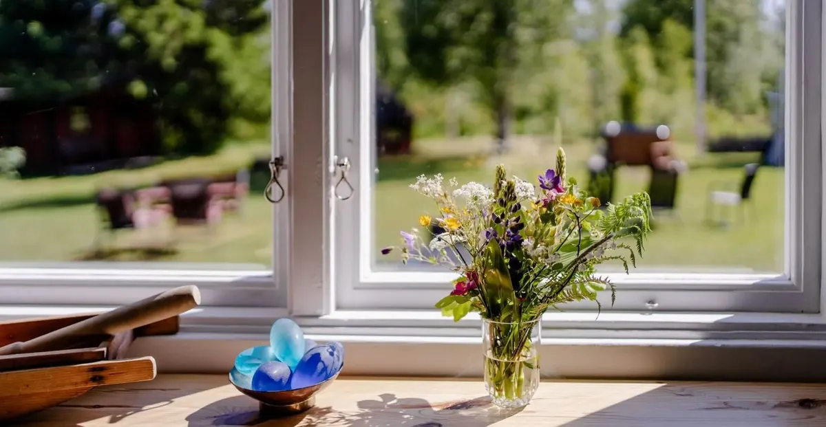 Fenster mit Wiesenblumenstrauß und Blick in den Garten